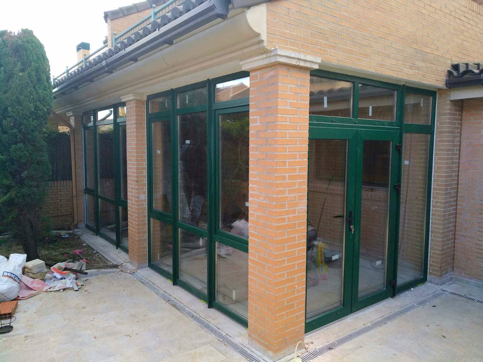 Окна и двери ПВХ REHAU поворотно-откидные установленные на террасе в Валенсии цвет зеленый, зеркальное стекло